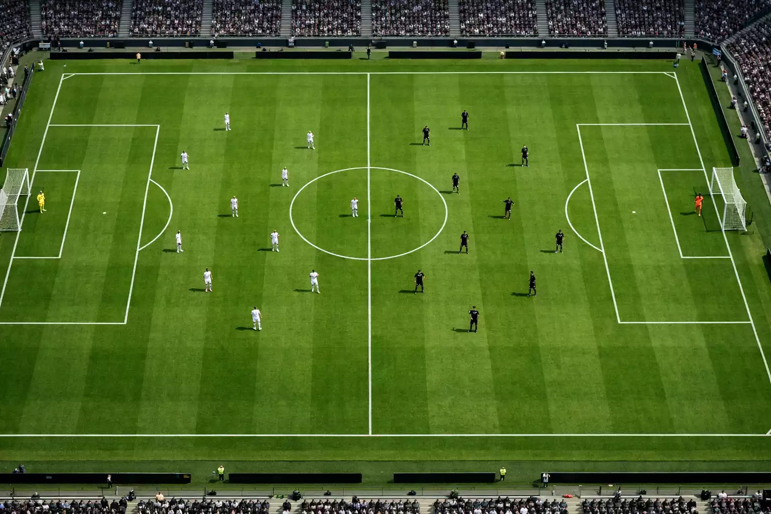 Voetbalveld vanuit vogelperspectief met spelers in actie tijdens een competitiewedstrijd